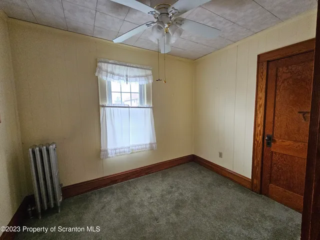 an empty room with a window and ceiling fan