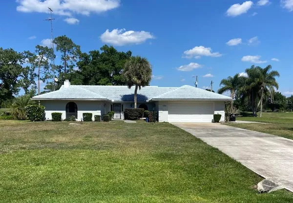 a front view of a house with a garden and trees