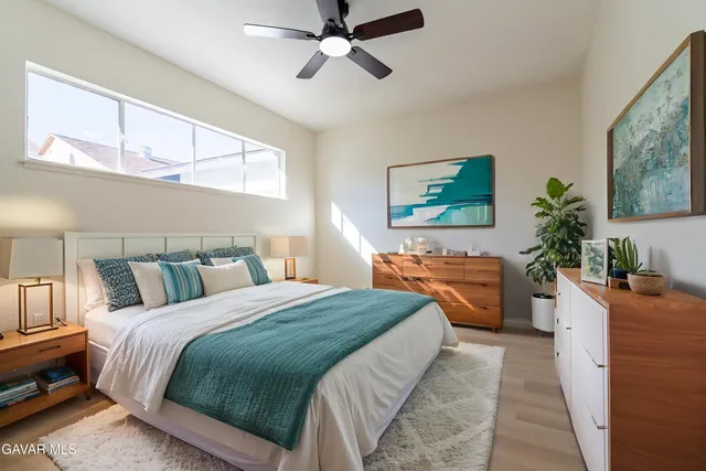 a bedroom with a large bed couch and windows