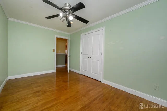 an empty room with wooden floor and a ceiling fan