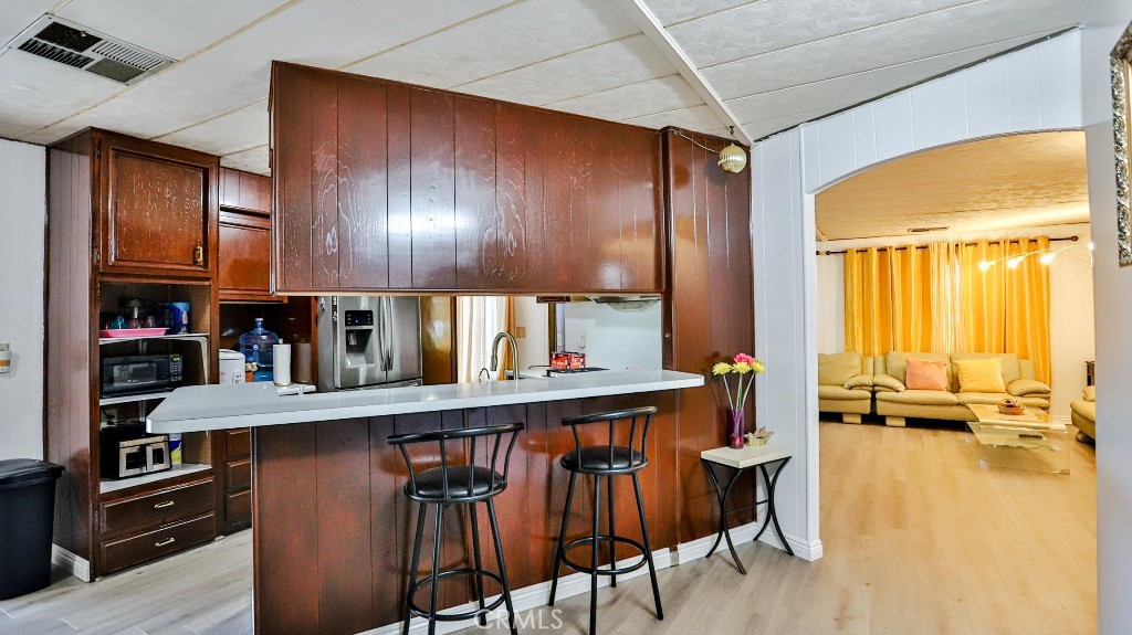 14300 Clinton Street, Unit 64 Garden Grove, CA 92843 - Photo 16 of 48 a kitchen with stainless steel appliances granite countertop a table chairs and a refrigerator