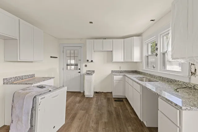 a kitchen with granite countertop a sink window and cabinets