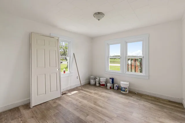 an empty room with wooden floor and windows