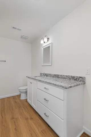 a bathroom with a granite countertop sink and a toilet