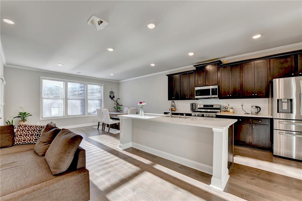 2230 Manor Pointe Drive Cumming, GA 30041 - Photo 17 of 53 a living room with stainless steel appliances kitchen island granite countertop a refrigerator a stove top oven a sink dishwasher and white cabinets with wooden floor