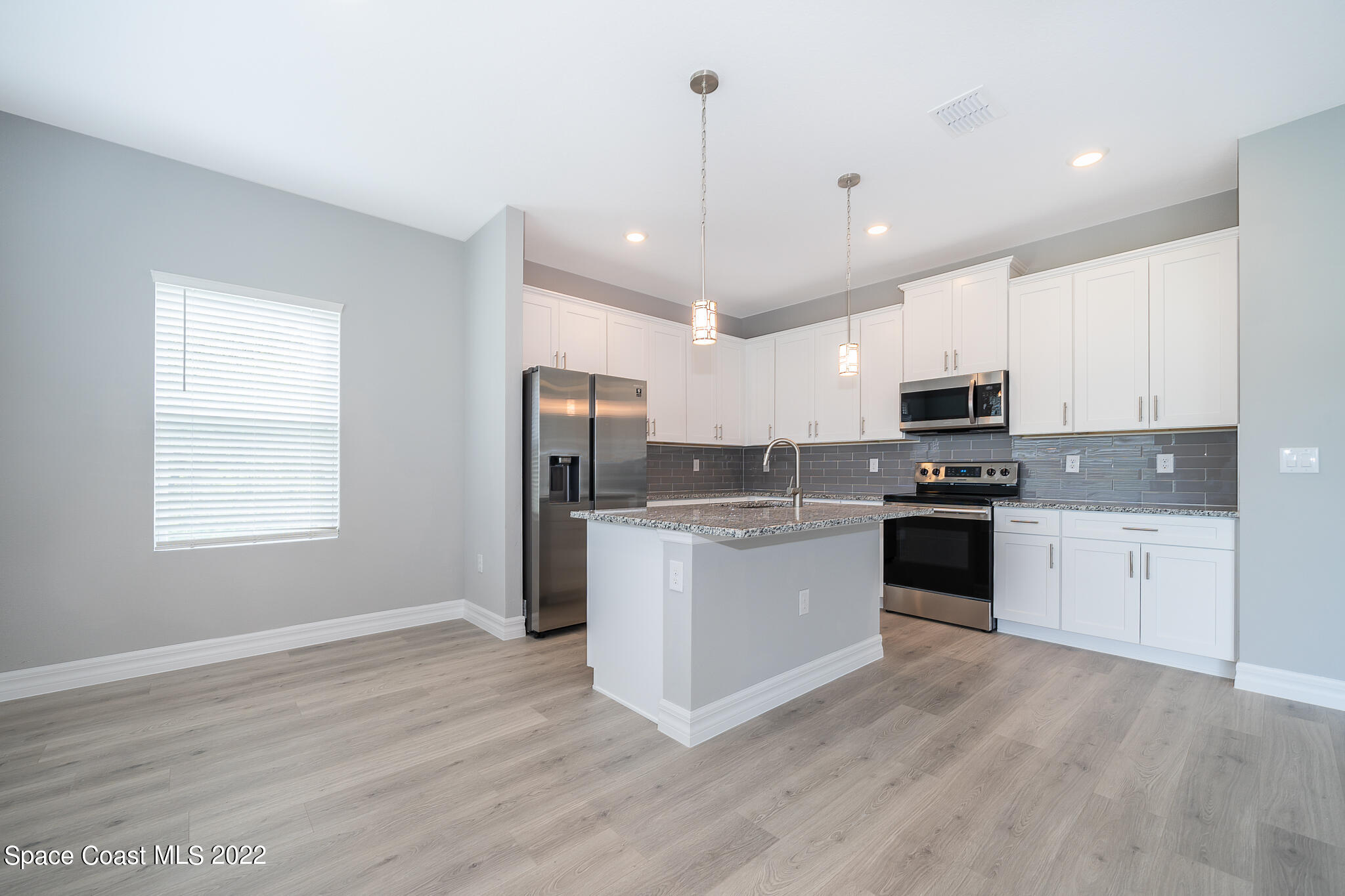 214 Gordon Road Northwest Palm Bay, FL 32907 - Photo 7 of 19 a kitchen with stainless steel appliances granite countertop a refrigerator oven a sink dishwasher and white cabinets with wooden floor
