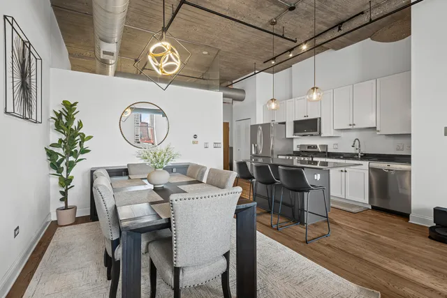 a living room filled with furniture a chandelier and kitchen view