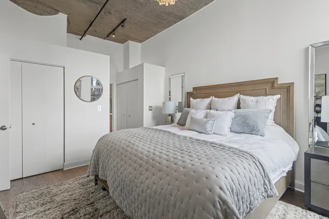 a bedroom with a bed a mirror and a chandelier