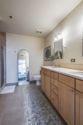 a spacious bathroom with a double vanity sink a mirror and toilet