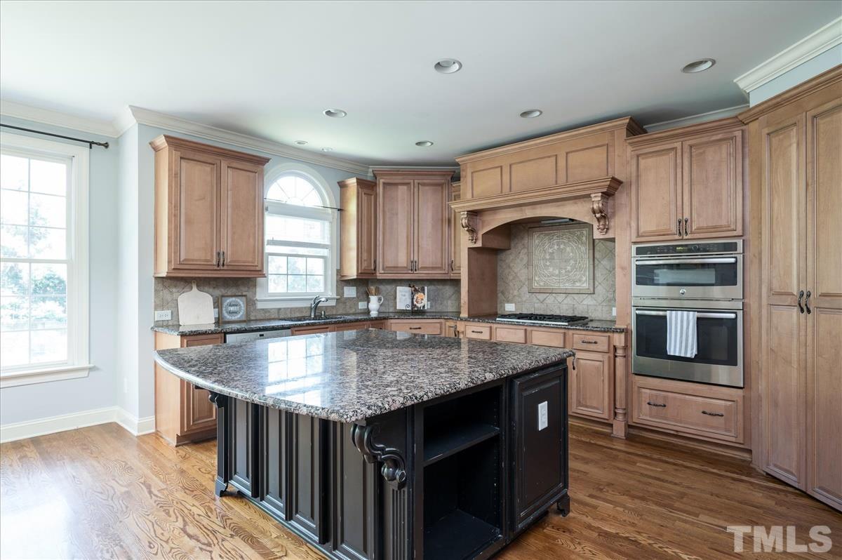 1917 Falls Farm Crossing Raleigh, NC 27614 - Photo 4 of 30 Gourmet Kitchen with custom cabinets, including cabinet vent hood over the gas cooktop, newer Stainless Steel Appliances, Granite Counters. and large distressed wood island.