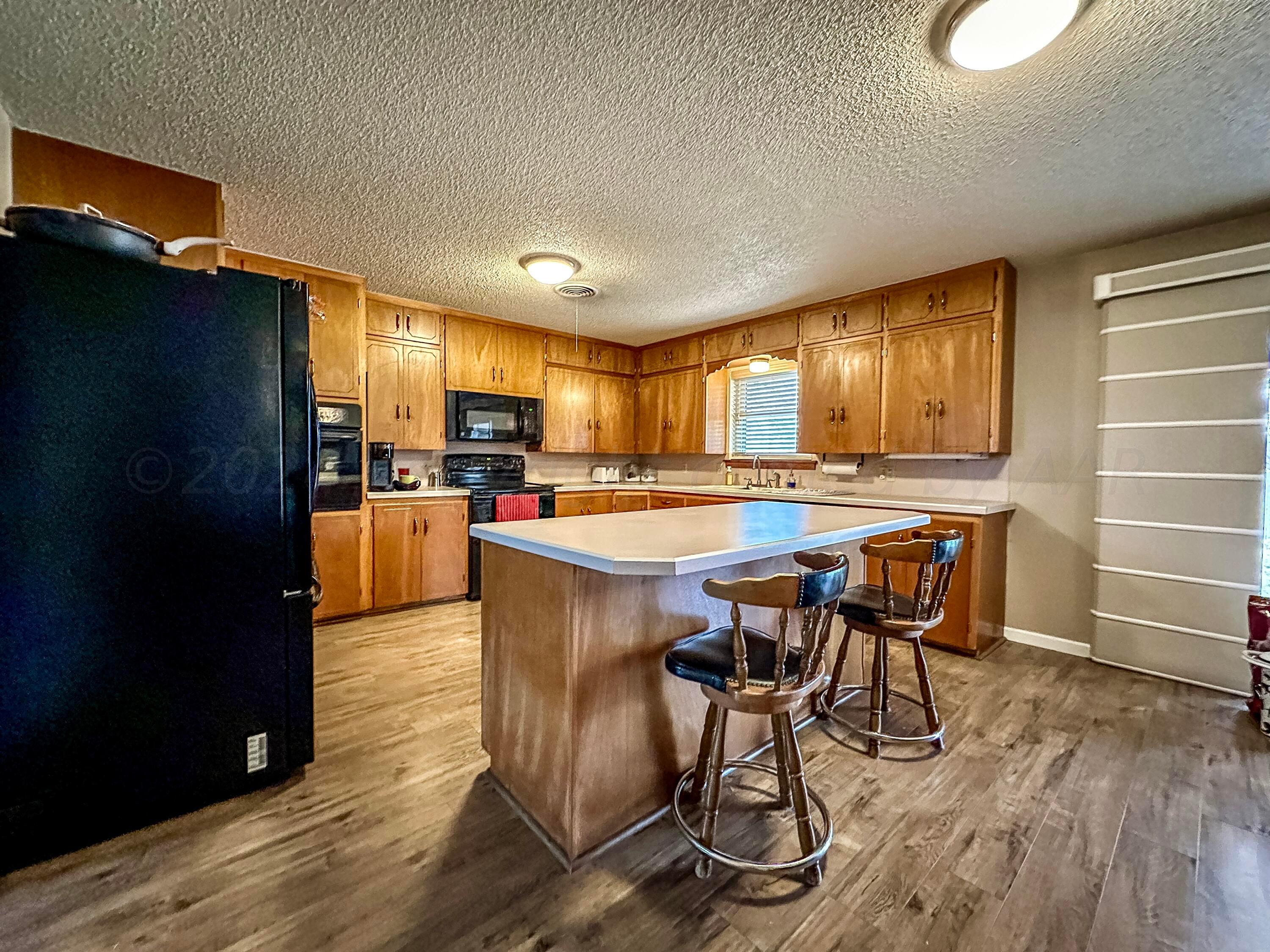 1404 Primrose Lane Borger, TX 79007 - Photo 12 of 27 a kitchen with stainless steel appliances kitchen island granite countertop a table chairs cabinets and wooden floor