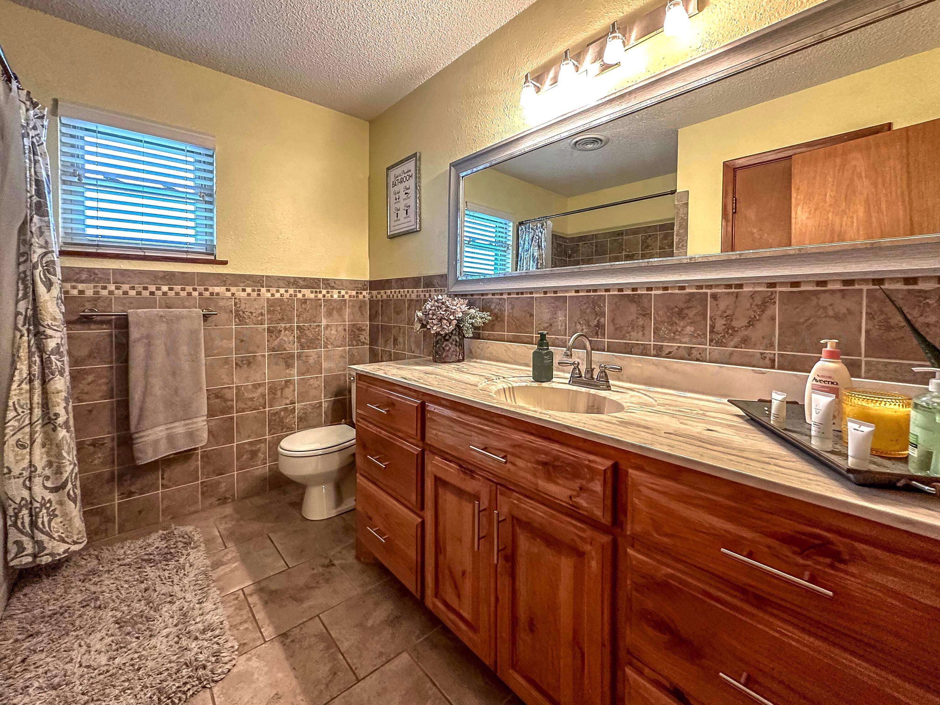 1404 Primrose Lane Borger, TX 79007 - Photo 15 of 27 a bathroom with a granite countertop double vanity sink a mirror and toilet