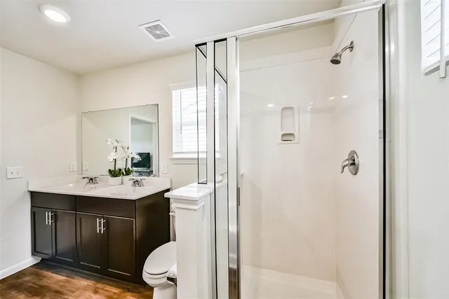 a bathroom with a sink a toilet a mirror and shower