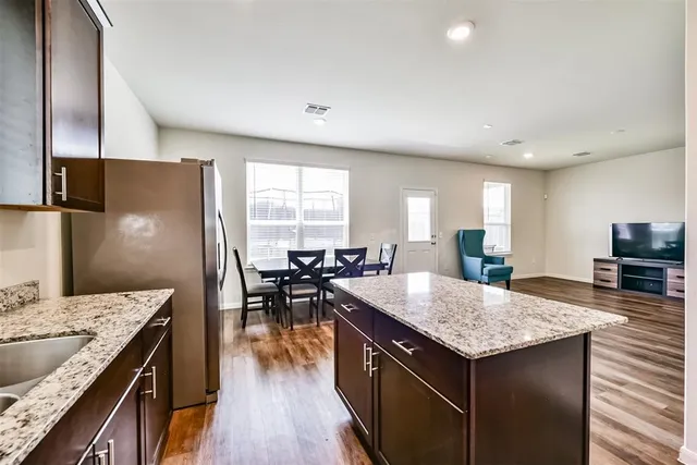 a kitchen with granite countertop kitchen island wooden floor and stainless steel appliances