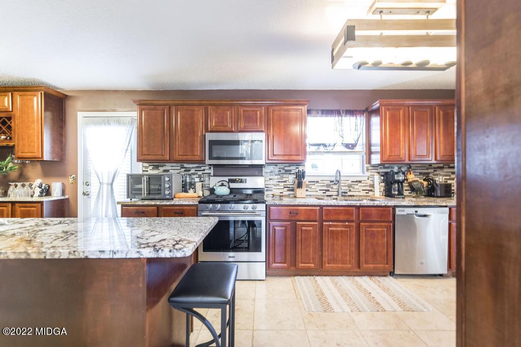 825 Kohl Drive McDonough, GA 30253 - Photo 11 of 59 a kitchen with stainless steel appliances granite countertop a stove top oven a sink dishwasher and cabinets with wooden floor