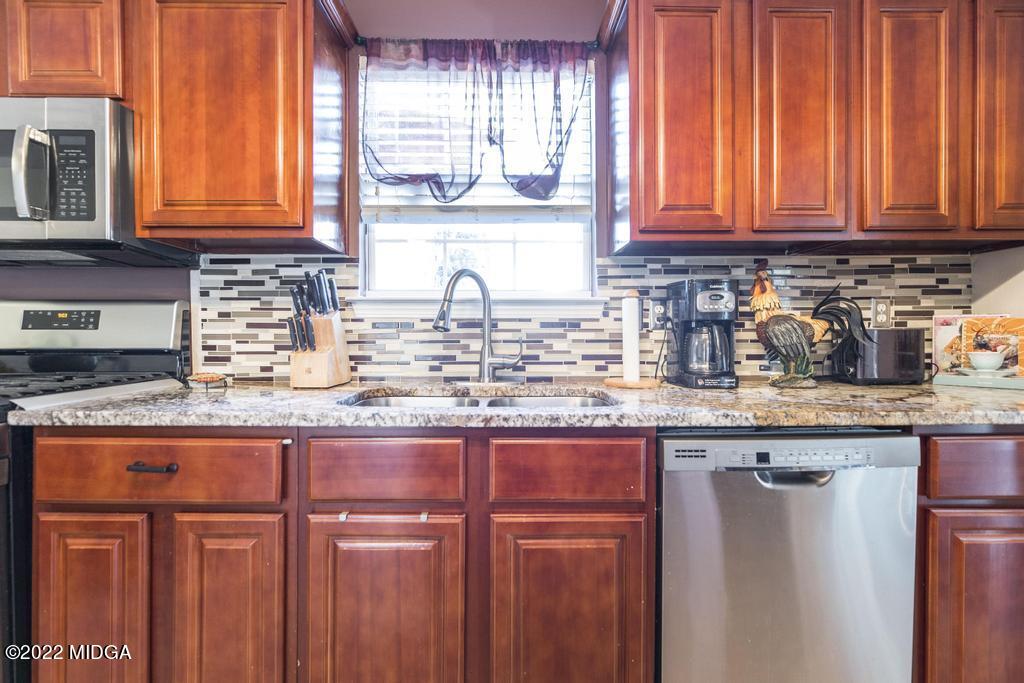 825 Kohl Drive McDonough, GA 30253 - Photo 12 of 59 a kitchen with granite countertop wooden cabinets a sink and a window