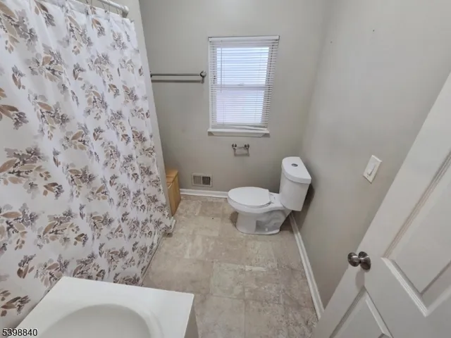 a bathroom with a toilet and a shower curtain
