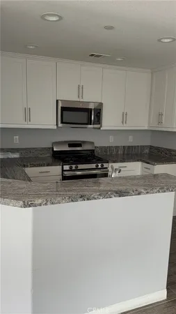 a kitchen with stainless steel appliances granite countertop a sink a stove a microwave and cabinets