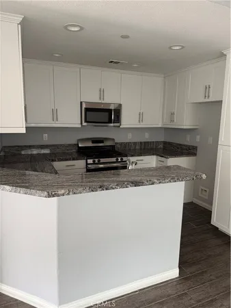 a kitchen with granite countertop a sink a stove a microwave and cabinets