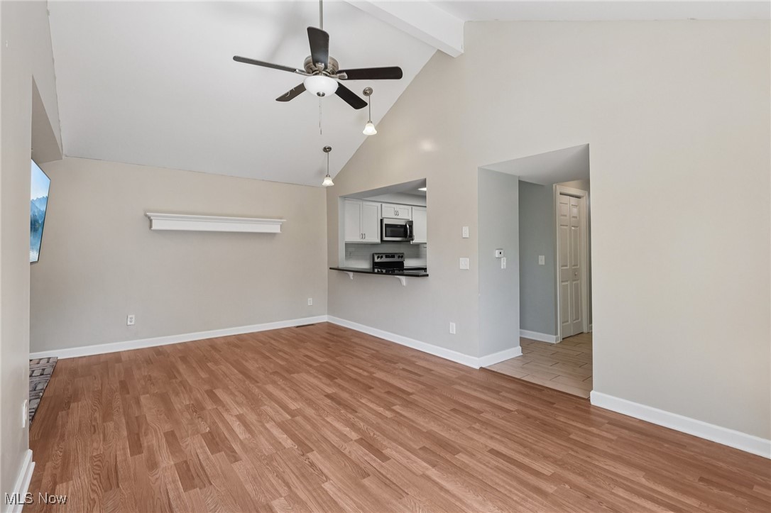 159 Eastland Road Berea, OH 44017 - Photo 6 of 38 Unfurnished living room featuring light wood-type flooring, a ceiling fan, high vaulted ceiling, and beamed ceiling