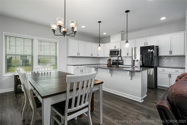 a kitchen with kitchen island a dining table chairs stainless steel appliances and cabinets