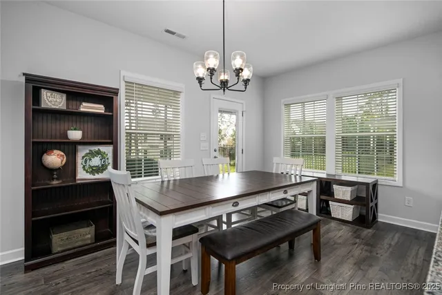 a dining room with wooden floor a chandelier a wooden table and chairs