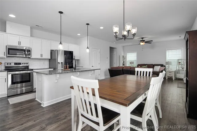 a kitchen with stainless steel appliances granite countertop a stove a refrigerator a kitchen island a dining table and chairs