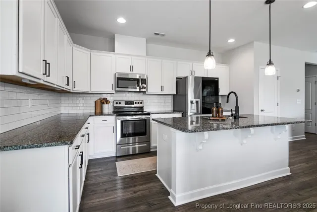 a kitchen with stainless steel appliances granite countertop a sink a stove and a refrigerator
