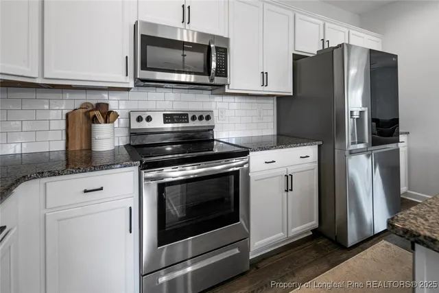 a kitchen with stainless steel appliances white cabinets a stove a microwave and a refrigerator
