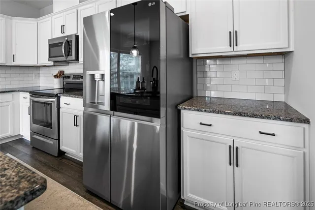 a kitchen with granite countertop white cabinets and stainless steel appliances