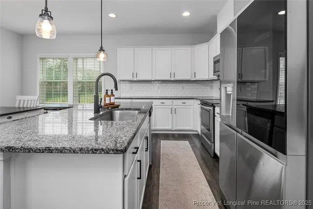 a kitchen with stainless steel appliances granite countertop a sink a stove and a refrigerator