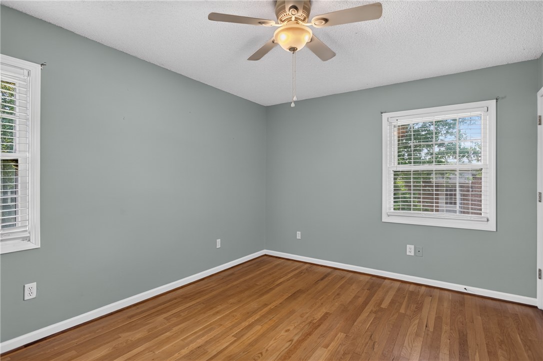 113 Greenfield Avenue Pendleton, SC 29670 - Photo 14 of 40 Hardwood flooring extends through this tranquil bedroom, offering abundant natural light and a cooling ceiling fan.