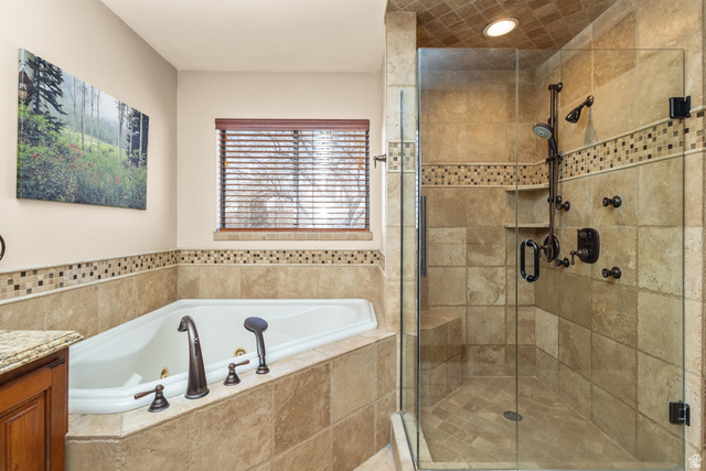 892 Cambridge Drive St. George, UT 84770 - Photo 51 of 65 Bathroom featuring a corner soaking tub with bronze fixtures, a tiled surround, and a separate glass-enclosed shower