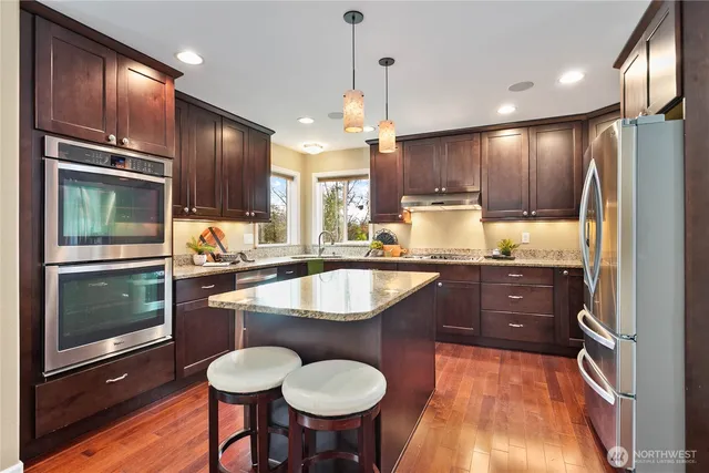 a kitchen with granite countertop a sink cabinets stainless steel appliances and a counter top space