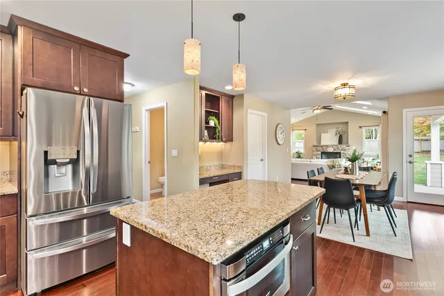 a kitchen with kitchen island a stove a refrigerator a dining table and chairs