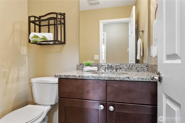 a bathroom with a granite countertop toilet sink and mirror