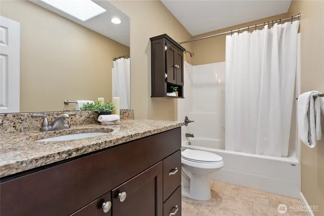 a bathroom with a granite countertop sink toilet and shower