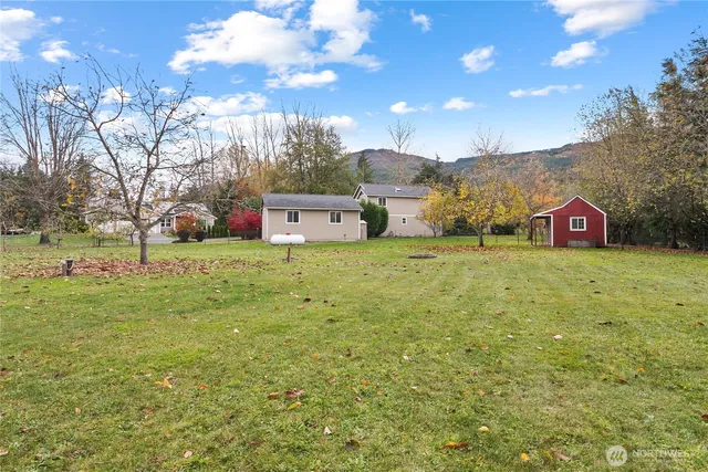 a view of a big house with a big yard and large trees