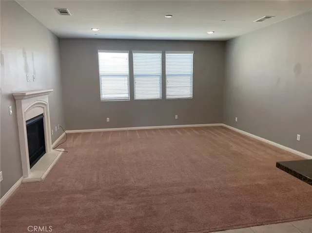 an empty room with windows and fireplace