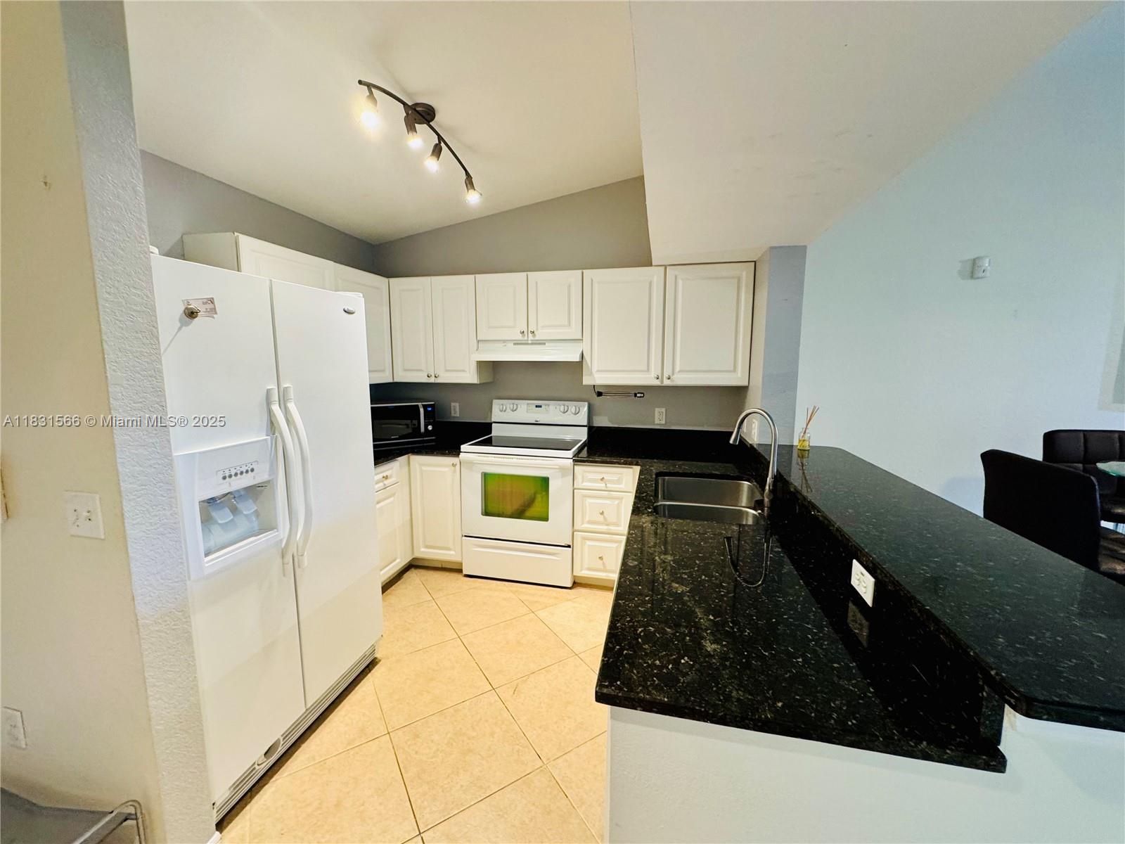 8244 Key Royal Circle, Unit 633 Naples, FL 34119 - Photo 12 of 37 a kitchen with granite countertop white cabinets and stainless steel appliances