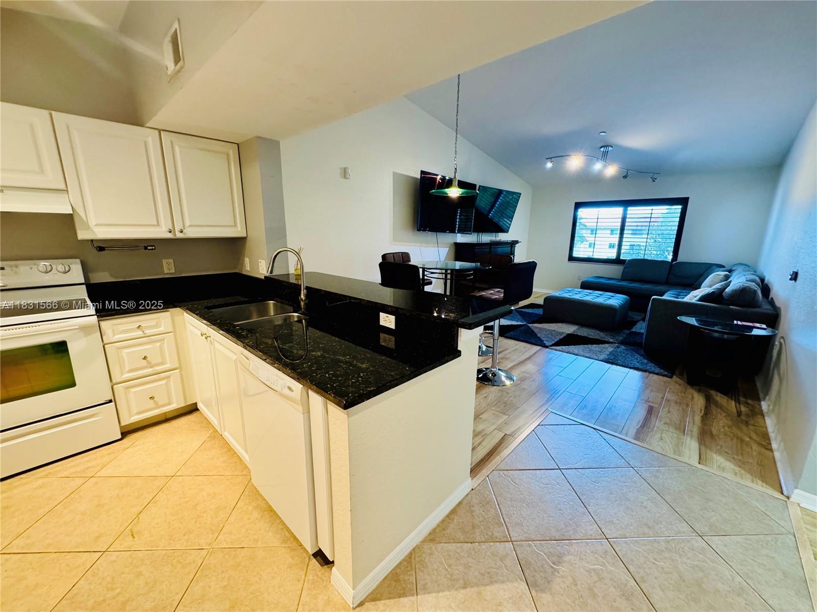 8244 Key Royal Circle, Unit 633 Naples, FL 34119 - Photo 14 of 37 a kitchen with granite countertop a sink a stove and cabinets