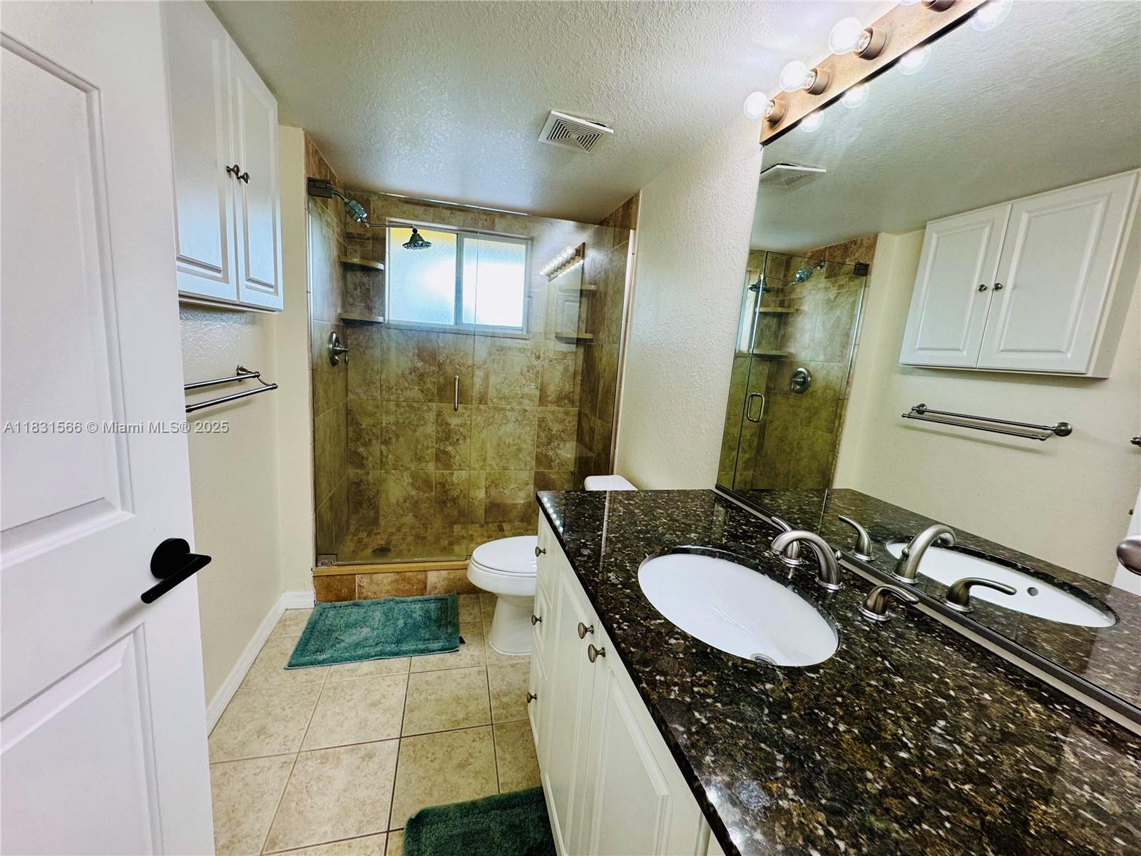 8244 Key Royal Circle, Unit 633 Naples, FL 34119 - Photo 5 of 37 a bathroom with a granite countertop sink a mirror and a shower