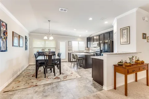 a kitchen with kitchen island a dining table chairs stainless steel appliances and cabinets