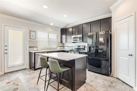 a kitchen with stainless steel appliances granite countertop a refrigerator a sink a stove a dining table and chairs