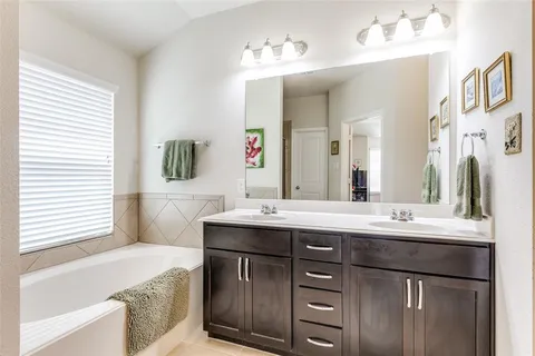 a bathroom with a sink double vanity granite tub shower and a mirror