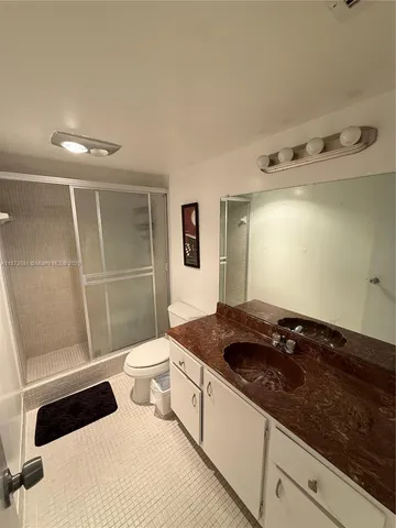 a bathroom with a granite countertop sink a toilet a mirror and shower