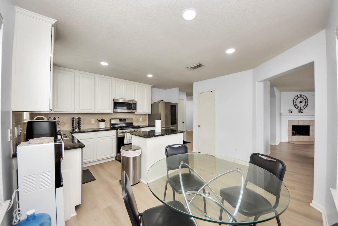 1054 Inverness Cove Dickinson, TX 77539 - Photo 11 of 28 a kitchen with stainless steel appliances kitchen island granite countertop a dining table chairs and a refrigerator