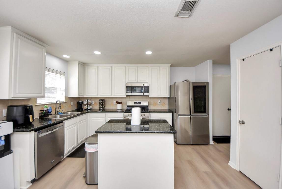 1054 Inverness Cove Dickinson, TX 77539 - Photo 13 of 28 a kitchen with refrigerator a microwave a sink and cabinets