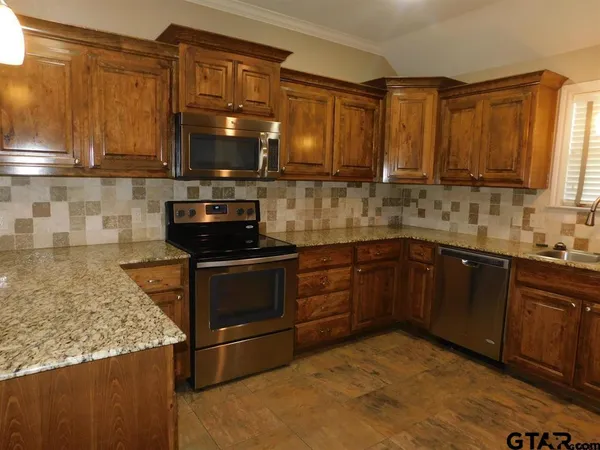 a kitchen with stainless steel appliances granite countertop a stove a sink and a microwave