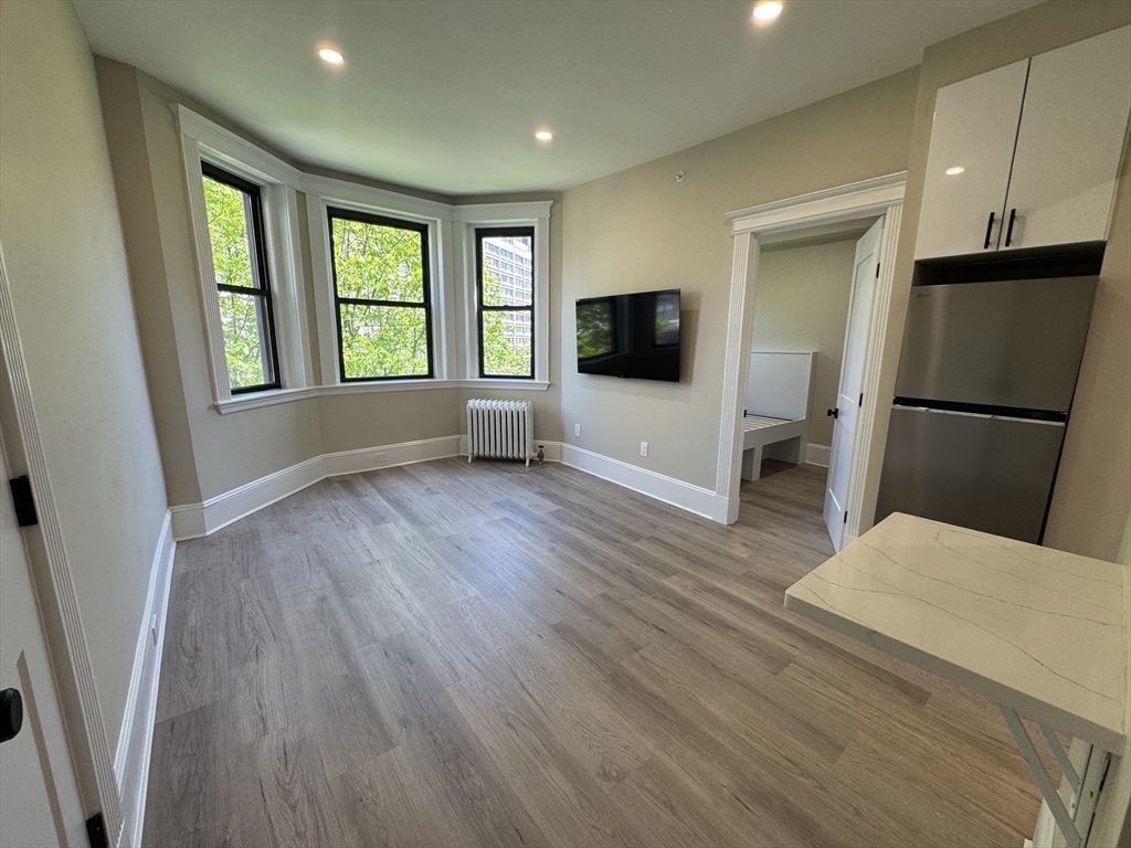 41 Edgerly Road, Unit 28 Boston, MA 02115 - Photo 3 of 13 a living room with a flat screen tv and a refrigerator
